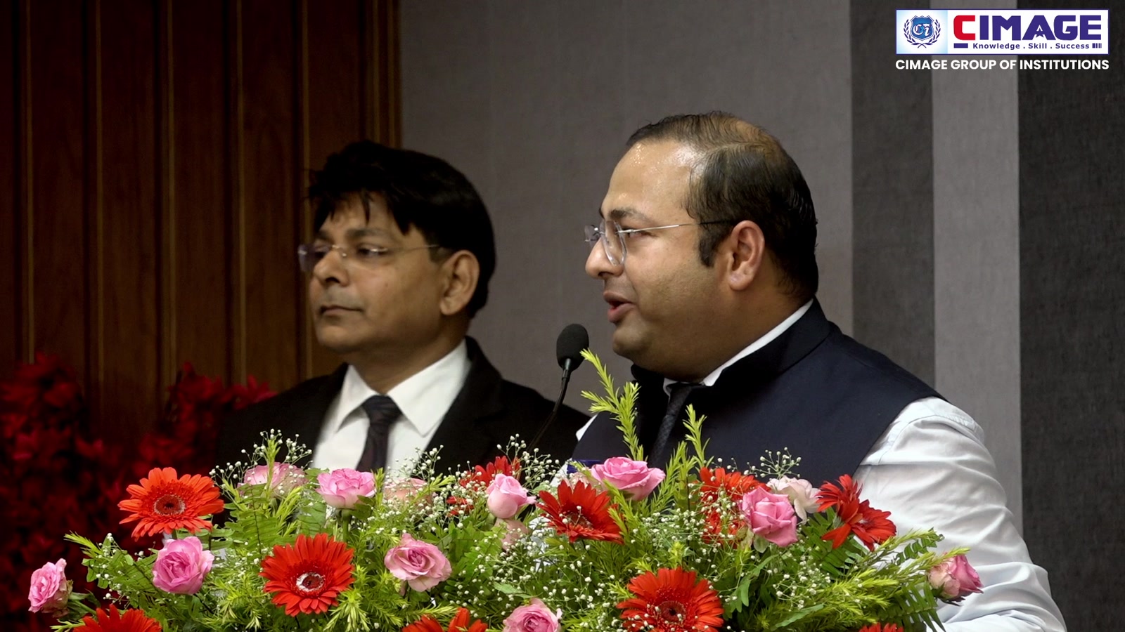 Two speakers standing behind a decorated podium at CIMAGE.